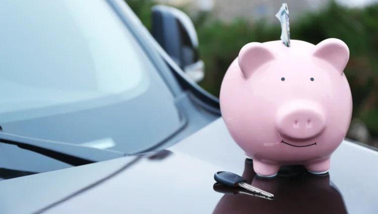 Pink piggy bank and car keys symbolizing savings on car insurance