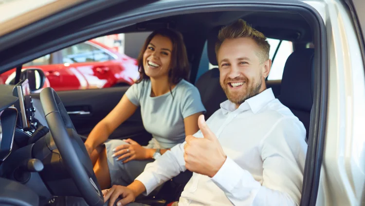 Happy couple sitting in their car after saving on car insurance