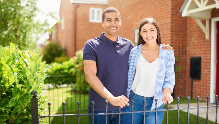 Smiling couple standing outside their home, representing peace of mind after securing the right home insurance policy.