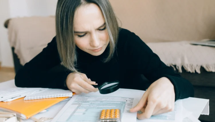 Woman carefully reading home insurance documents with a magnifying glass to check the fine print